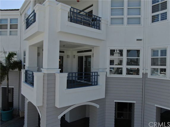 Front view of a multi-story building with balconies and blue railings.