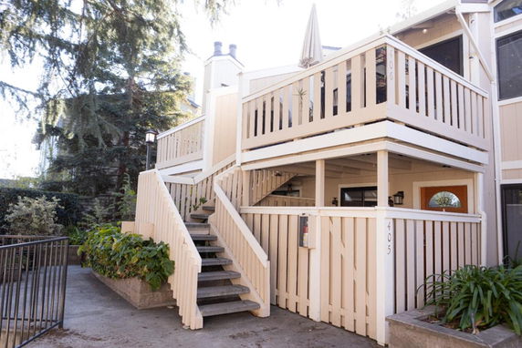 Front view of a two-story house with wooden railings and stairs.