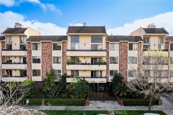 Front view of a multi-story apartment building with brick and beige exterior finish.