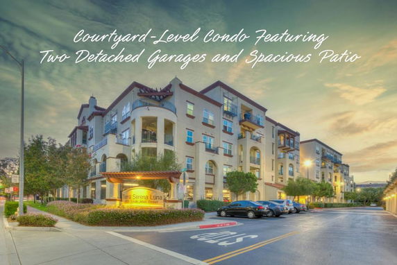 Front view of a multi-story condo building with balconies and two detached garages.