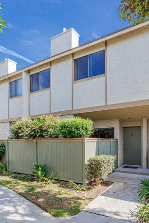 Front view of a two-story townhouse with a small fenced yard.