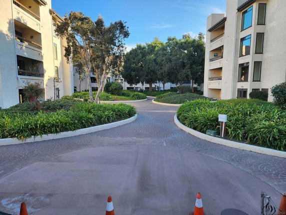 Front view of multiple-story residential buildings with balconies and landscaped pathways.