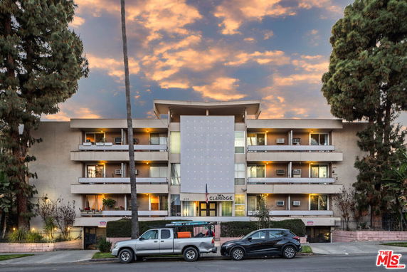 Front view of a multi-story apartment building with balconies and a central entrance.