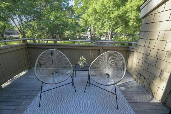 Balcony area with two chairs overlooking trees and a neighborhood.