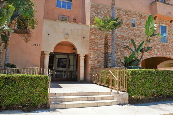 Front view of a multi-story building with an arched entrance and stone facade.