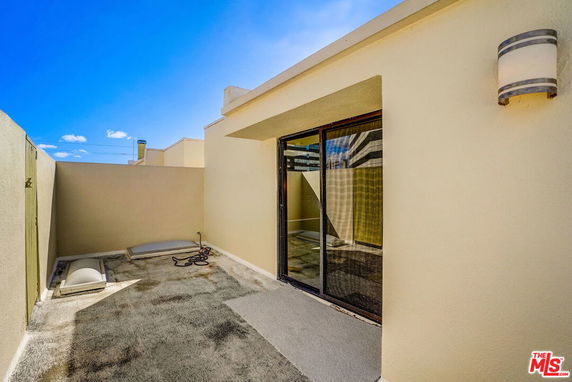 Rooftop area with sliding glass door and wall-mounted light.
