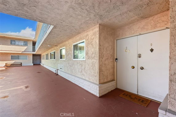 Exterior view of a multi-story residential building with a corridor and entrance doors.