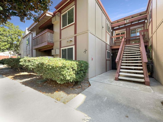 Front view of a multi-story apartment building with external staircase.