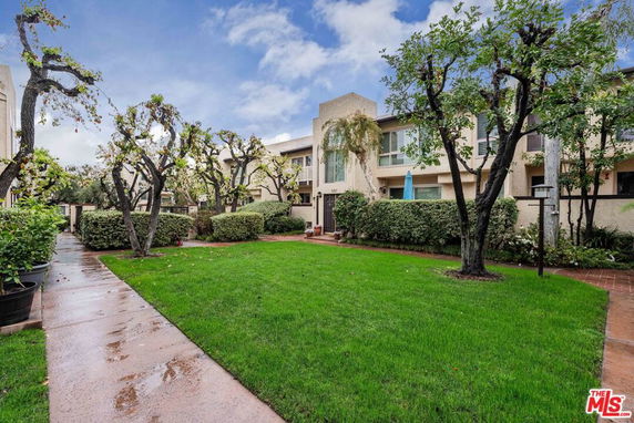 Front view of a multi-story residential building with landscaped garden and pathway.