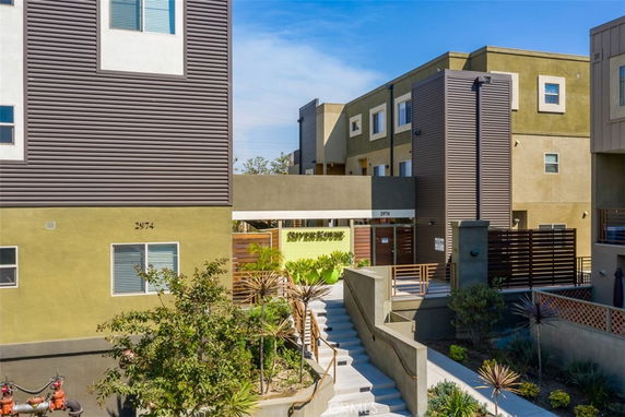 Front view of a modern multi-story apartment building with a gated entrance.