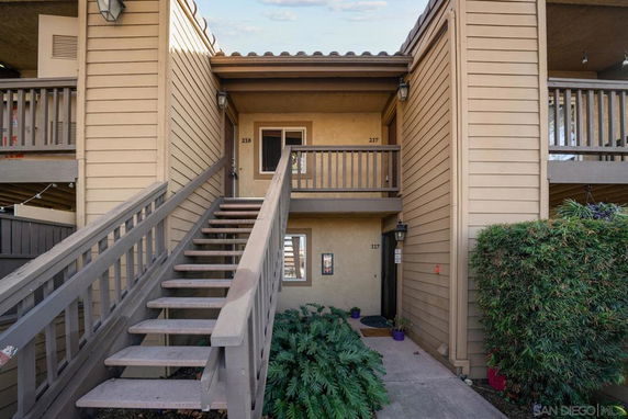 Front view of a multi-story apartment building entrance with exterior stairs.