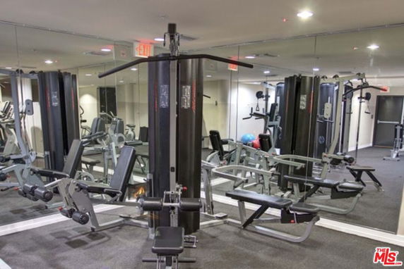 Interior view of a gym area with fitness equipment and mirrored walls.