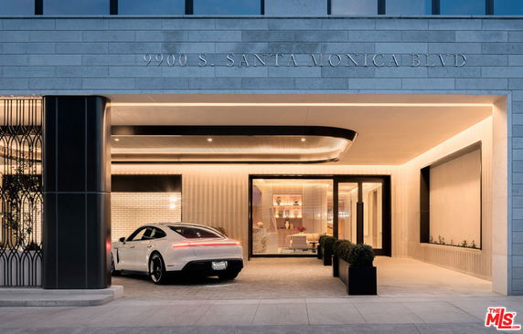 Front view of a modern building entrance with a drive-through area and parked car.