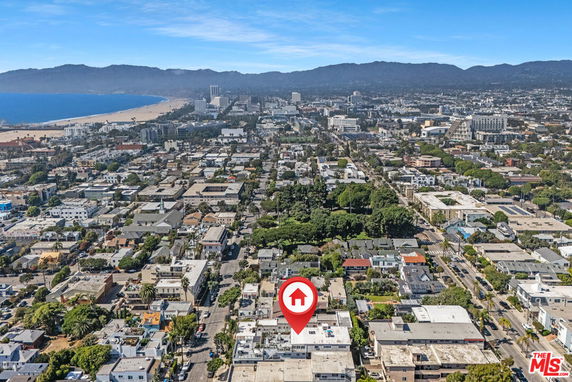 Aerial panoramic view of a city with numerous buildings and a beach in the distance.