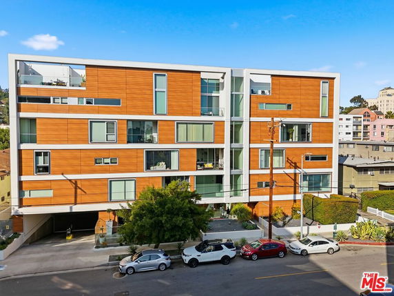 Front view of a multi-story modern apartment building with wood paneling and large windows.