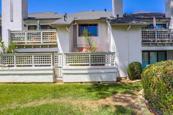 Front view of a two-story house with balconies and a white fence.