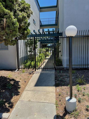 Front view of a building entrance with a gated pathway and multiple stories.