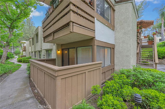 Front view of a multi-story residential building with balconies and wooden fencing.