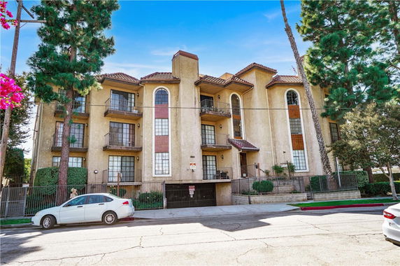 Front view of a multi-story apartment building with balconies and large windows.