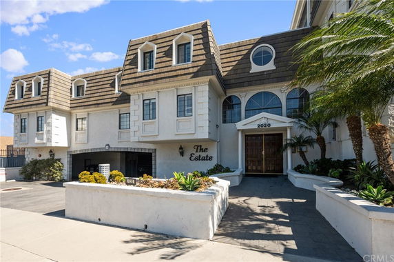 Front view of a large multi-story residential building with a distinctive roof design and decorative windows.