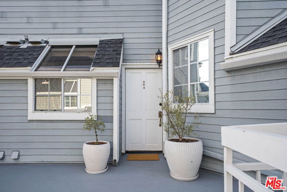 Front view of a house with a white door and two potted plants.