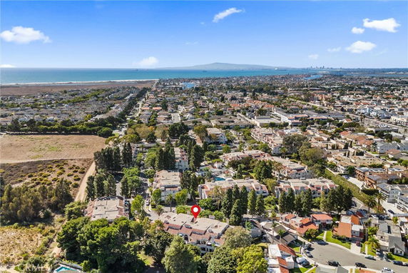 Panoramic view of a coastal residential area with houses, trees, and ocean in the background.