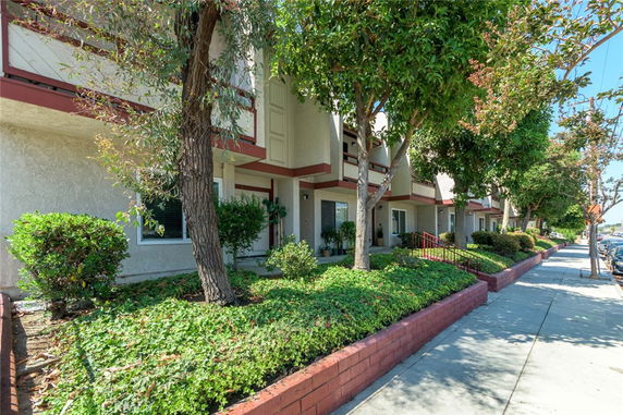 Front view of a multi-story residential building with balconies and a landscaped walkway.