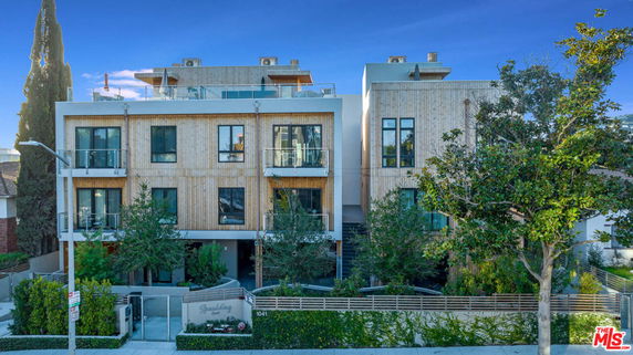 Front view of a modern four-story apartment building with a wooden facade.
