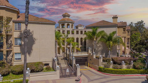 Front view of a multi-story building with decorative architecture and palm trees.