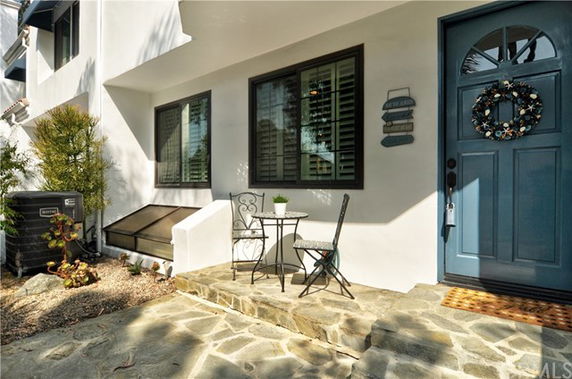 Front view of a house with a blue door and small patio area.