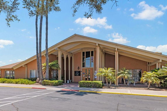 Front view of a large building with a sloping roof and tall windows.