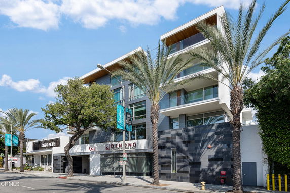 Front view of a modern multi-story building with large windows and balconies.