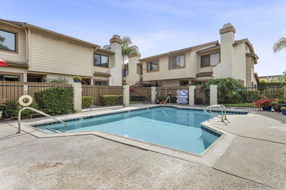 Outdoor view of a residential complex with a fenced swimming pool area.