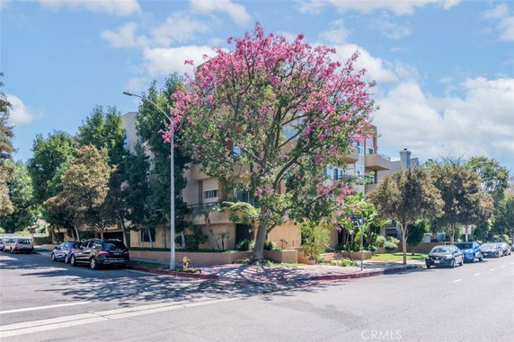 Front view of a multi-story building with balconies and surrounding trees.