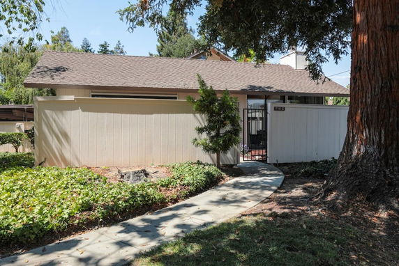Front view of a single-story house with a sloped roof and gated entry.