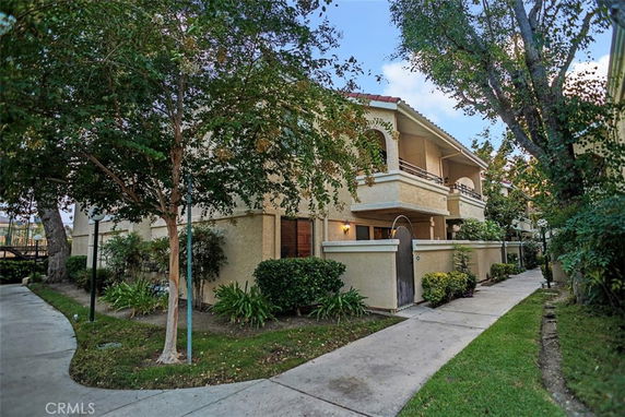 Front view of a multi-story residential building with balconies and pathway.