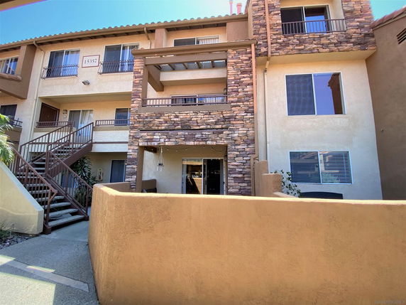 Front view of a multi-story apartment building with stone and stucco facade.