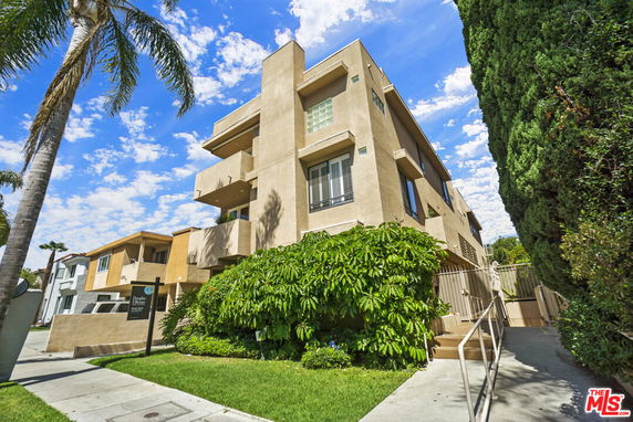 Front view of a multi-story apartment building with beige exterior and balconies.