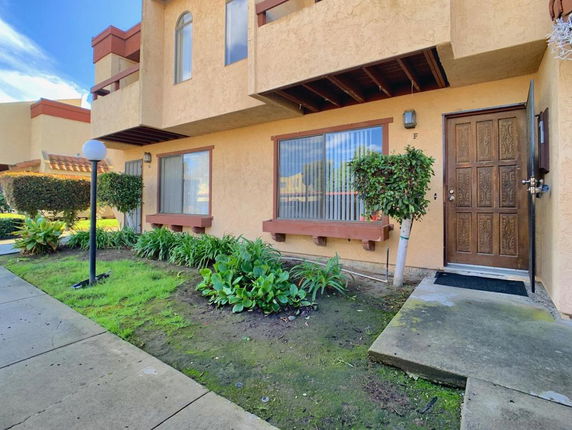 Front view of a two-story house with a wooden door and large windows.