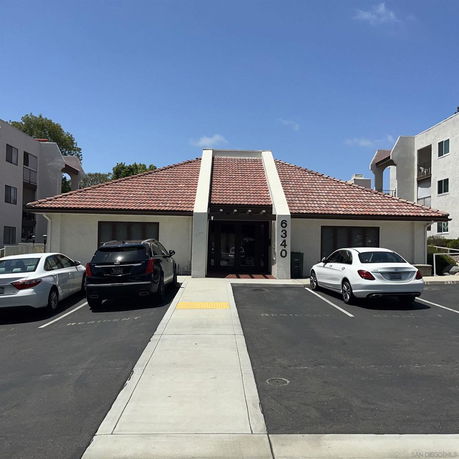 Front view of a building with a tiled roof and parking area in front.