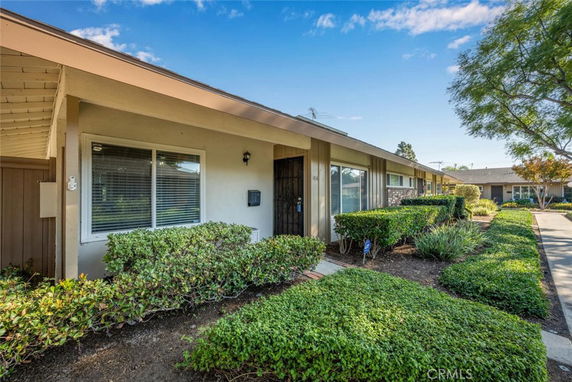 Front view of a single-story house with large windows and shrubbery.