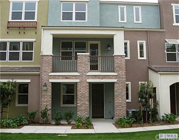 Front view of a multi-story townhouse with a small porch and multiple windows.