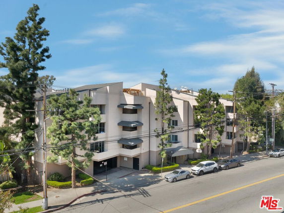 Front view of a multi-story building with balconies and a covered entrance.