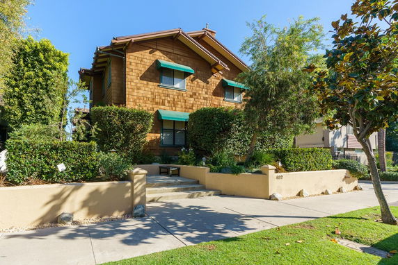 Front view of a two-story house with wooden exterior and green awnings.