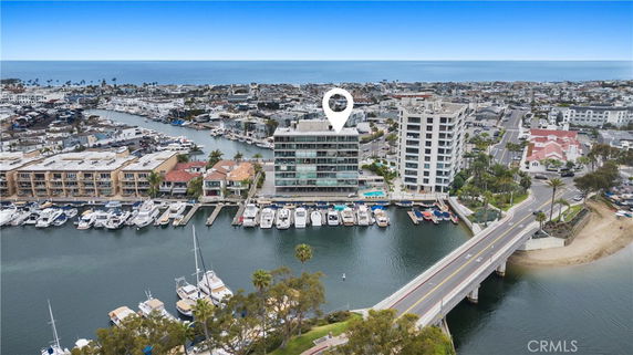 Aerial view of a waterfront building with a marina and surrounding urban area.