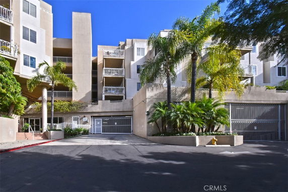 Front view of a multi-story residential building with balconies and a gated entrance.