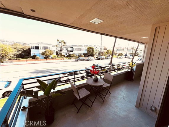 Panoramic view from a building balcony overlooking a street and surrounding houses.