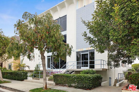 Front view of a modern two-story building with large windows and a metal railing staircase.