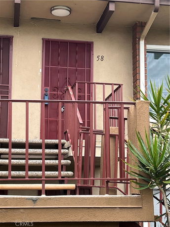 Front view of an apartment with a staircase and red metal door.
