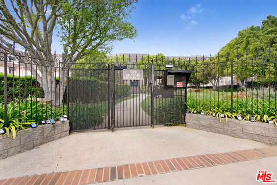 Front view of a gated entrance with wrought iron fencing leading to a residential complex.